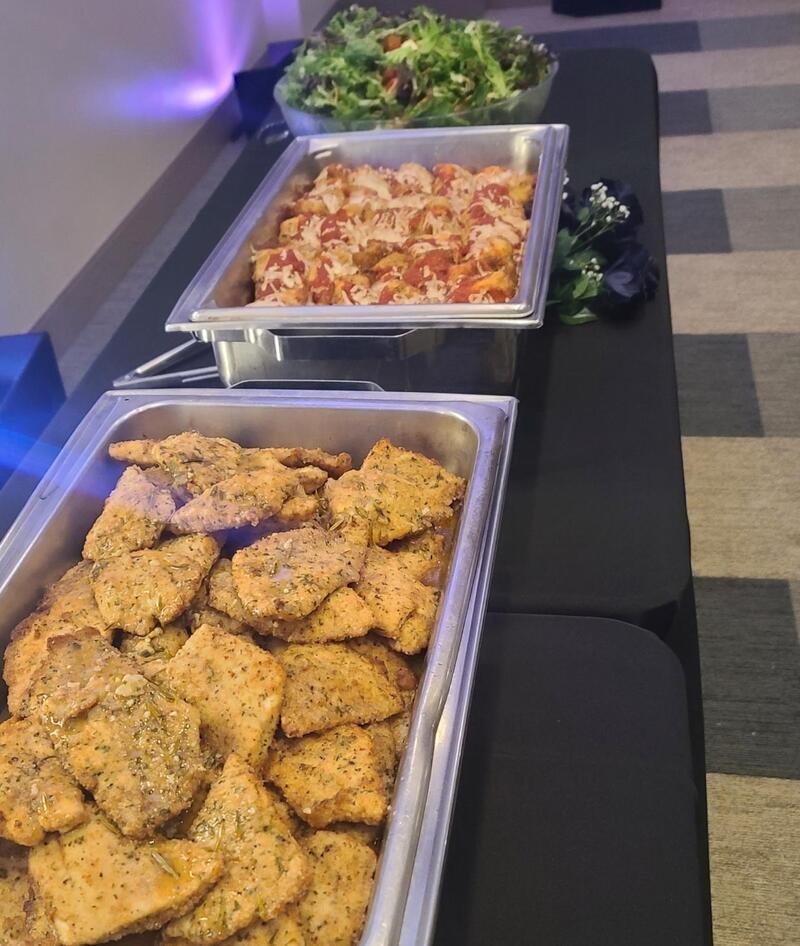 Chafing trays of chicken and salad on a buffet table