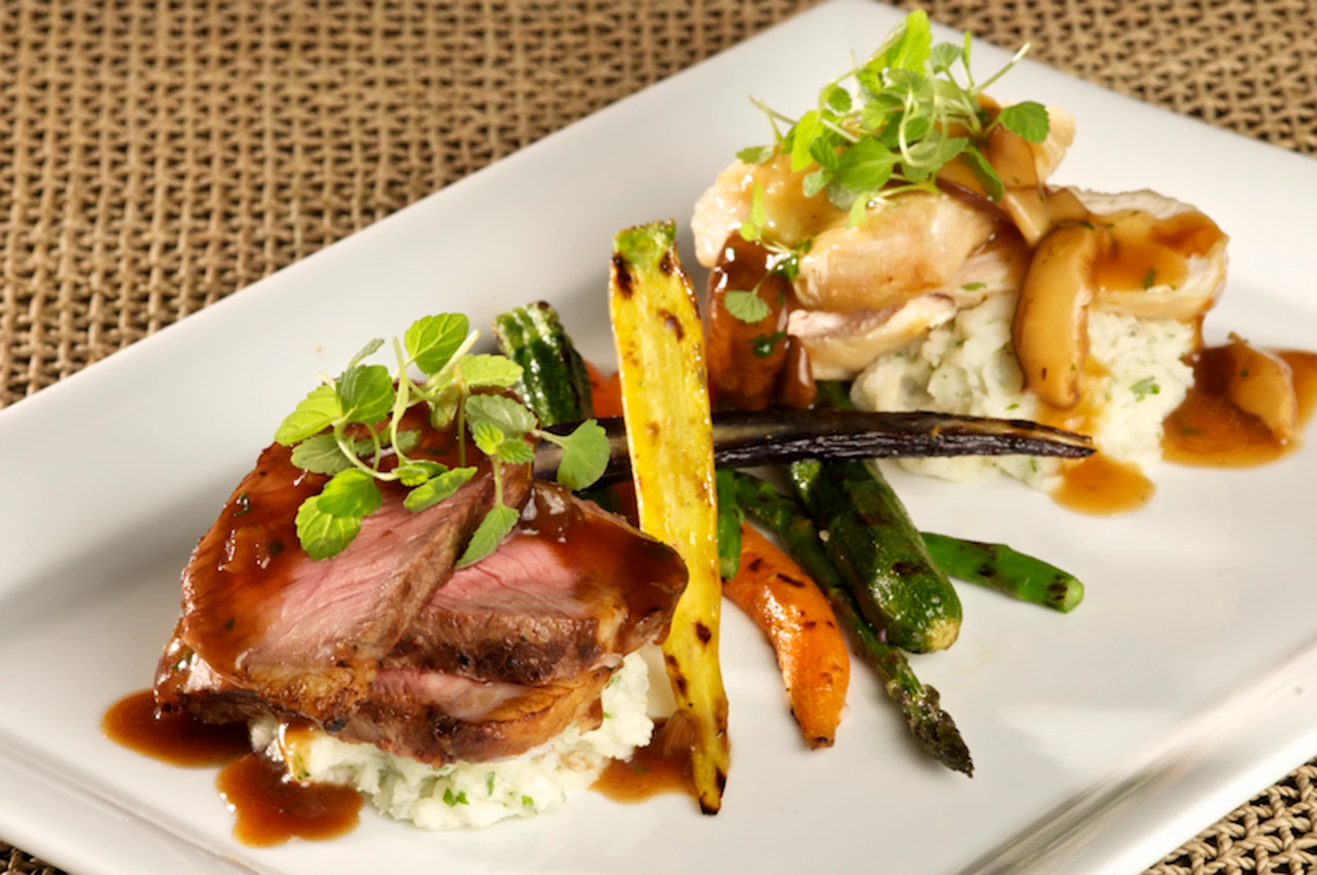 Plated beef and chicken duet with mashed potatoes and grilled vegetables