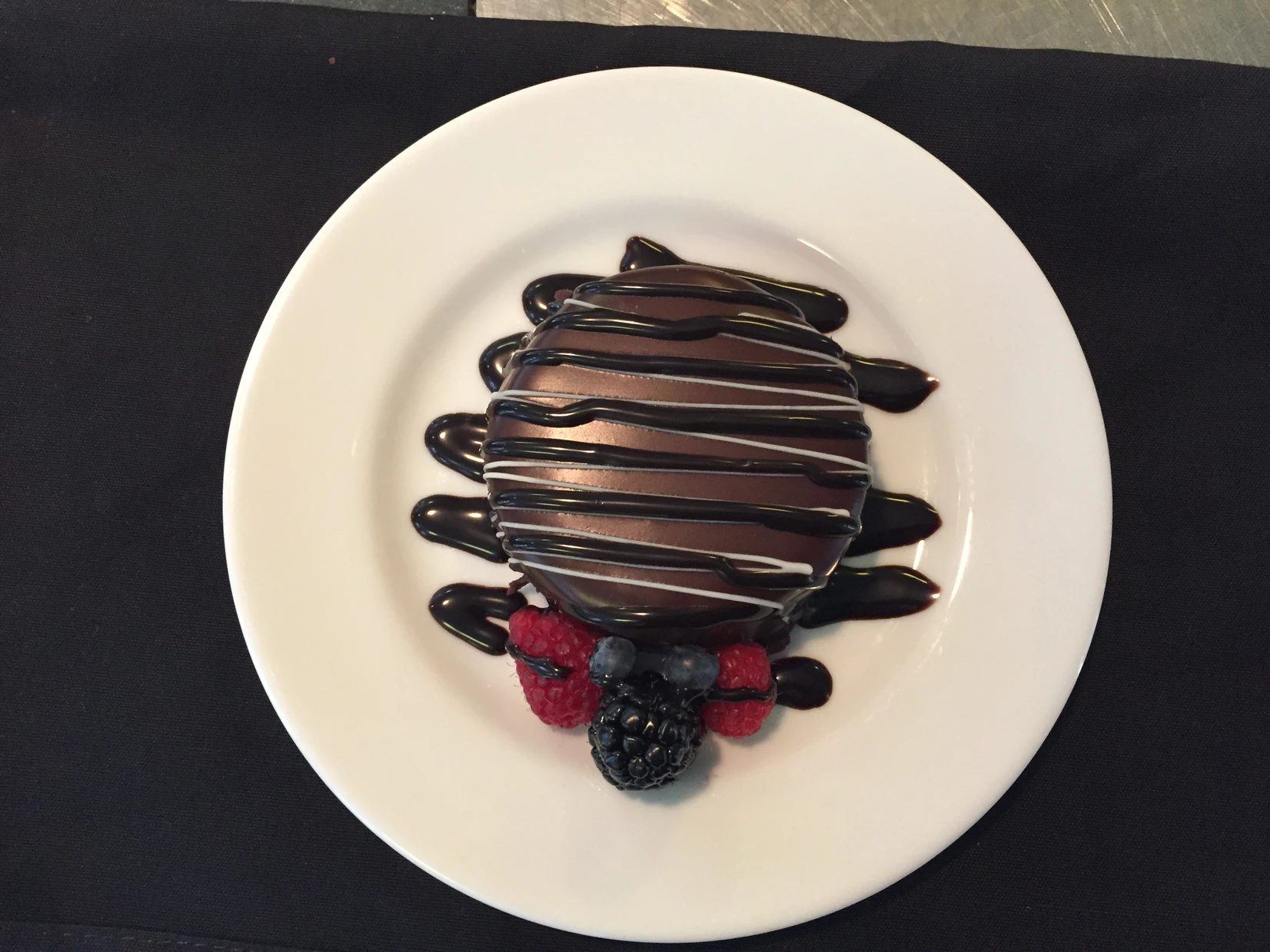 Chocolate glazed dessert plated with fresh berries